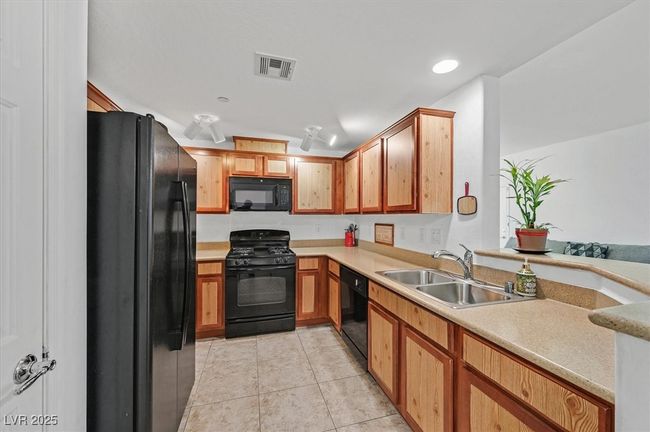 Kitchen featuring black appliances, light tile patterned flooring, light countertops, and recessed lighting | Image 7