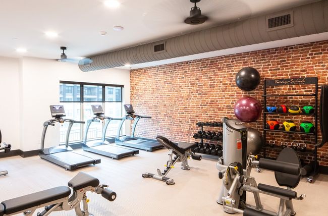 Workout area with ceiling fan, brick wall, and visible vents | Image 17