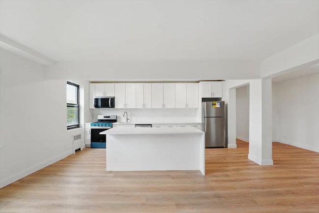 Kitchen with radiator, stainless steel appliances, white cabinets, and light countertops | Image 6