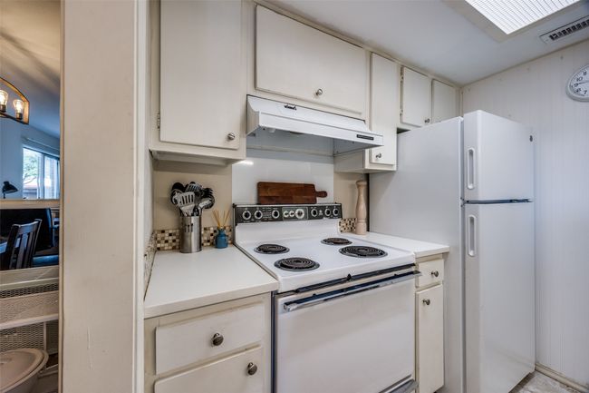 Kitchen featuring white appliances, under cabinet range hood, light countertops, and white cabinetry | Image 9