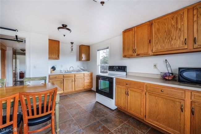 Kitchen with brown cabinetry, range with electric cooktop, light countertops, and a sink | Image 30