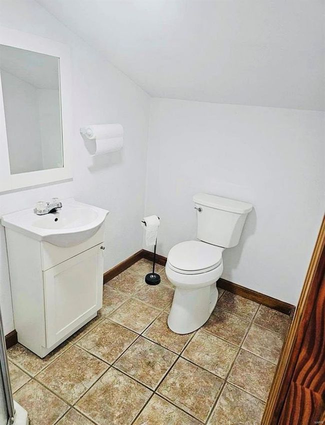 Half bathroom featuring baseboards, vaulted ceiling, toilet, and vanity | Image 18