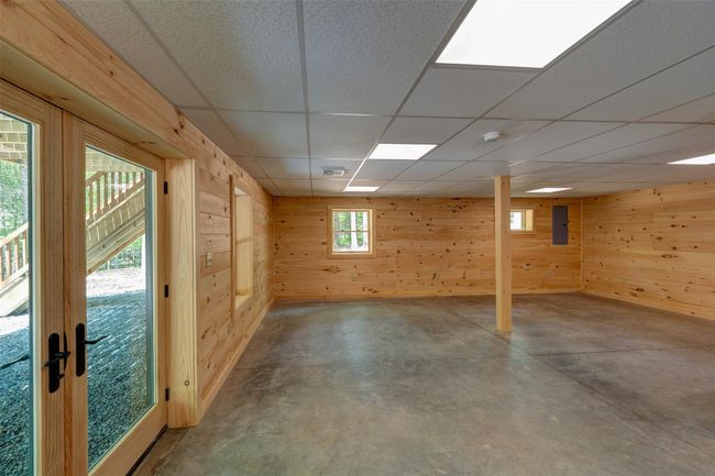 Basement with wooden walls, a drop ceiling, and electric panel | Image 34