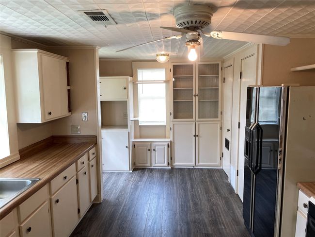Kitchen with refrigerator ceiling fan, dark wood-style floors, crown molding, and a sink | Image 10