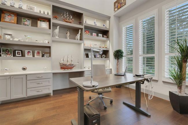 The bright, modern home office with built-in shelving, large windows with plantation shutters. | Image 11