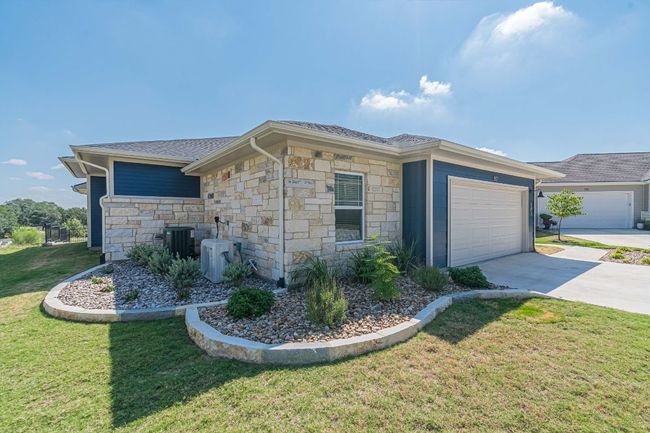 View of side of home with concrete driveway, an attached garage, a yard, stone siding, and roof with shingles | Image 36