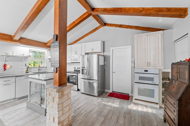 Kitchen featuring white cabinets, decorative backsplash, light stone counters, and stainless steel appliances | Image 8