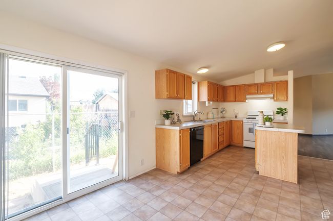 Kitchen with gas range gas stove, dishwasher, light countertops, under cabinet range hood, and vaulted ceiling | Image 5