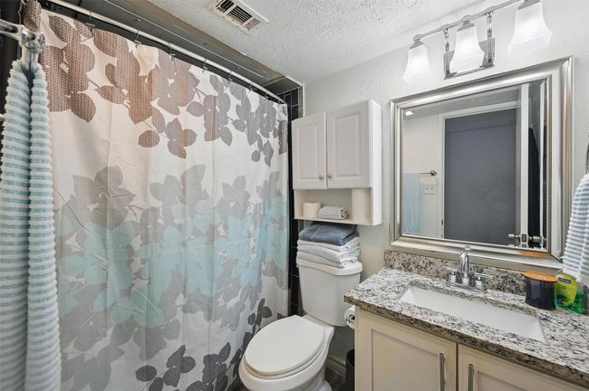 Bathroom with vanity, a shower with curtain, a textured wall, and a textured ceiling | Image 23