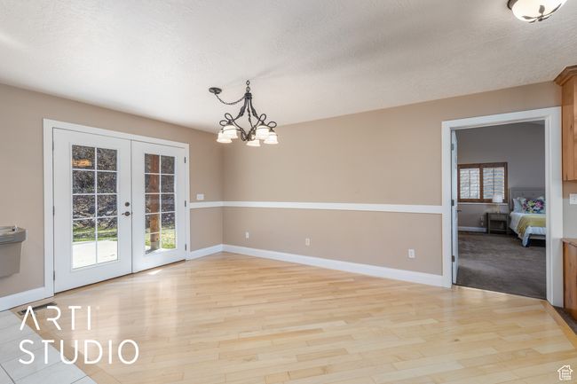 Unfurnished dining area featuring light wood-style floors, a textured ceiling, french doors, baseboards, and a notable chandelier | Image 19