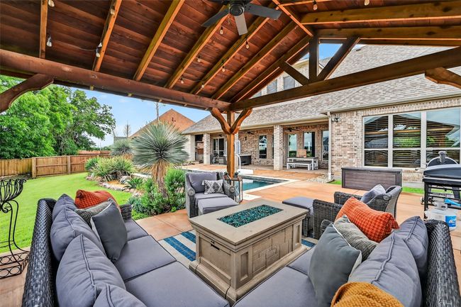 Fenced backyard featuring an outdoor living space with a fire pit, a patio area, and a ceiling fan | Image 40