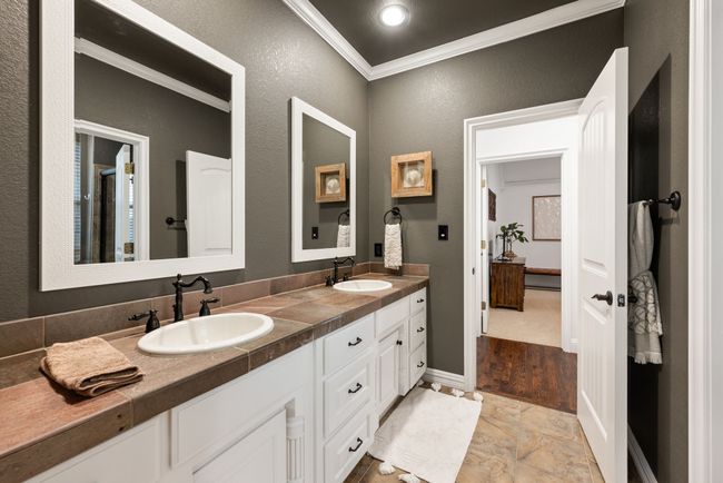 Full bathroom upstairs with double vanity, framed mirrors, crown molding, tile flooring, and bronze fixtures and hardware. | Image 27