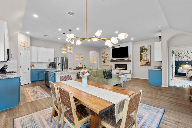 Dining space with wood finished floors, recessed lighting, a lit fireplace, arched walkways, and baseboards | Image 8