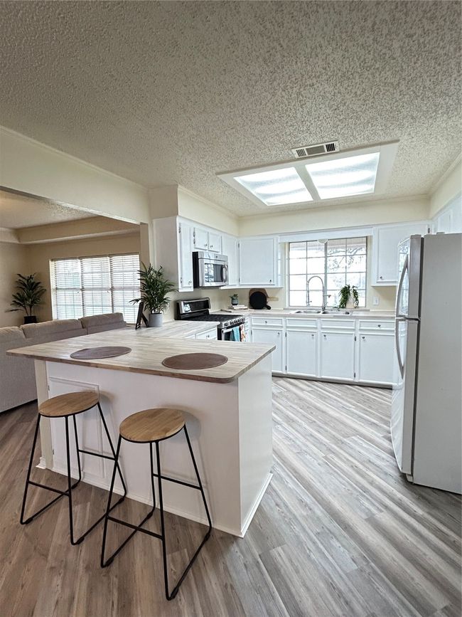 Kitchen with light wood-type flooring, a peninsula, range, fridge, and a sink | Image 12