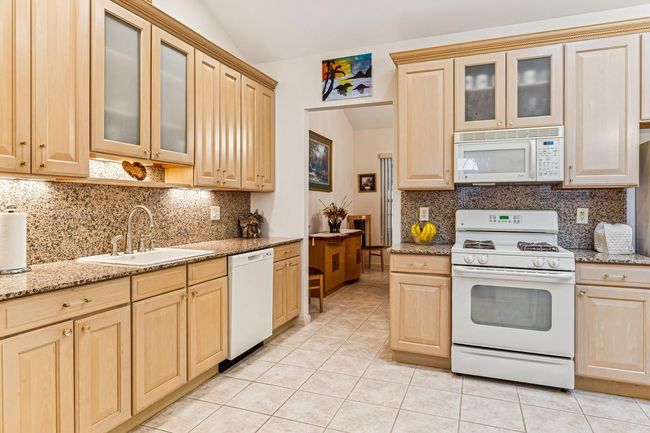 Kitchen featuring light tile patterned flooring, lofted ceiling, a sink, and white appliances | Image 29