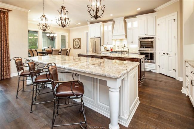 Kitchen featuring appliances with stainless steel finishes, a spacious island, a sink, premium range hood, and an inviting chandelier | Image 9