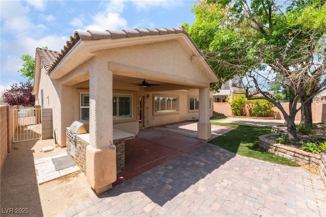 Back of property featuring exterior kitchen, a ceiling fan, stucco siding, a patio area, and a fenced backyard | Image 47