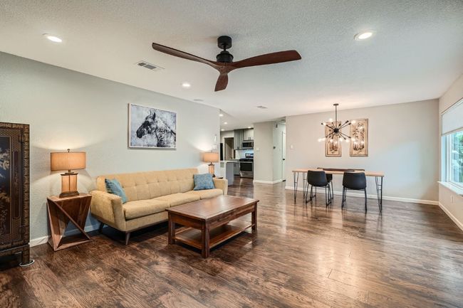 Living room featuring dark wood-style floors, a chandelier, a textured ceiling, a ceiling fan, and recessed lighting | Image 12