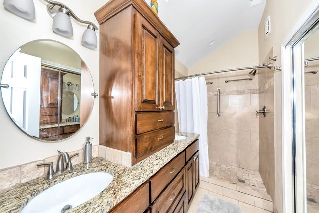 Full bath with lofted ceiling, tiled shower, double vanity, and tile patterned flooring | Image 22
