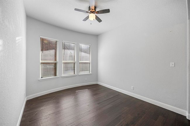 Empty room featuring a ceiling fan, dark wood-style flooring, and baseboards | Image 9