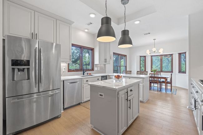 Kitchen with stainless steel appliances, a peninsula, a kitchen island, tasteful backsplash, and light wood finished floors | Image 13