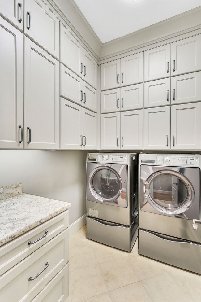 The main level laundry room has stylish cabinets, ideal for home organization. The washer and dryer convey with the home! | Image 35