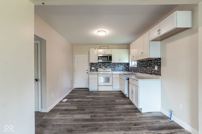kitchen with white range with electric cooktop, light countertops, stainless steel microwave, tasteful backsplash, and a sink | Image 15