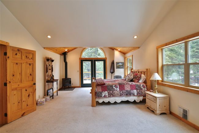 Bedroom featuring visible vents, carpet flooring, a wood stove, and vaulted ceiling | Image 42