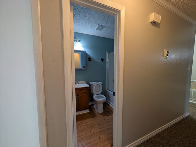 Full bathroom with a textured ceiling, toilet, visible vents, shower / bath combination, and vanity | Image 17