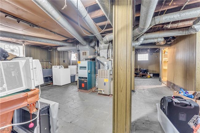 Below grade area featuring wooden walls, heating unit, visible vents, and washer / clothes dryer | Image 24