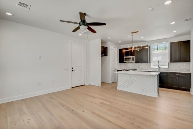 Kitchen featuring stainless steel microwave, decorative backsplash, light wood-style flooring, recessed lighting, and light countertops | Image 7