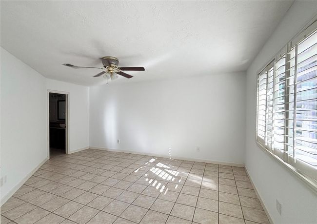 Master bedroom with large window and premium plantation shutter and ceiling fan | Image 10