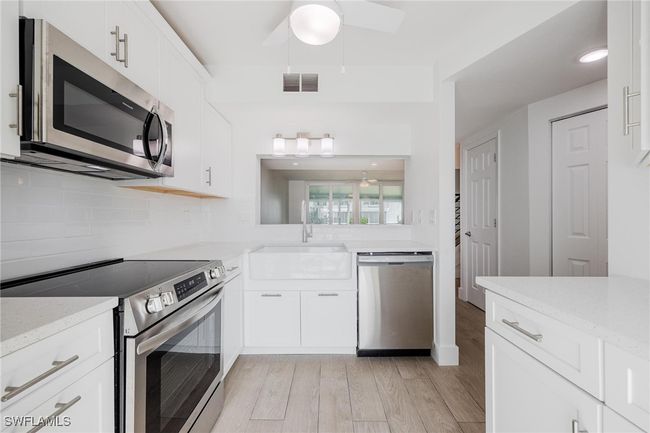 Kitchen with pass-through window with view of the living room. | Image 8