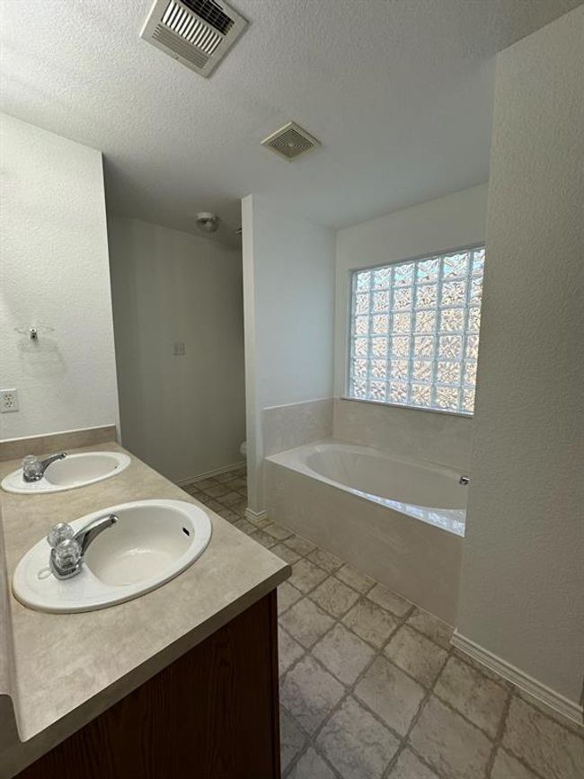 Bathroom featuring a bath, double vanity, and a textured ceiling | Image 10
