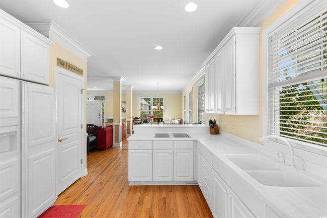 Kitchen with a sink, crown molding, white cabinetry, ornate columns, and recessed lighting | Image 7