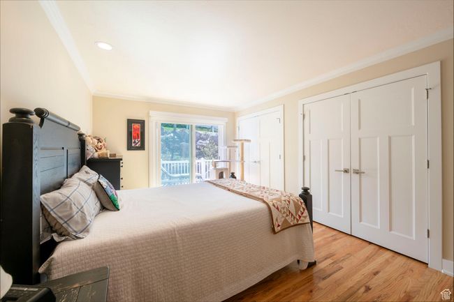 Bedroom featuring ornamental molding, recessed lighting, two closets, access to exterior, and wood finished floors | Image 11