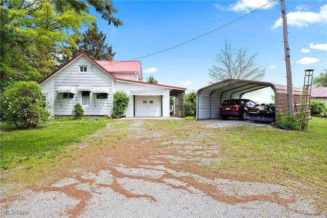 View of front of house, a detached carport, a front yard, an attached garage, and metal roof | Image 12