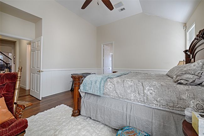 Bedroom with visible vents, a ceiling fan, wainscoting, lofted ceiling, and wood finished floors | Image 32