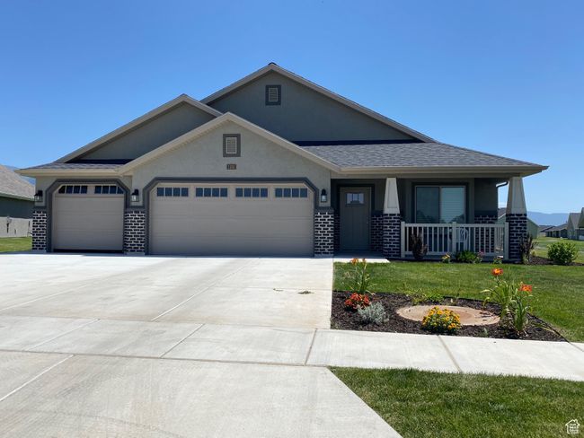 View of front of home with a front lawn, stucco siding, driveway, a porch, and a garage | Image 5