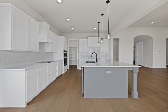 Kitchen with tasteful backsplash, arched walkways, recessed lighting, a kitchen island with sink, and light wood-style flooring | Image 12
