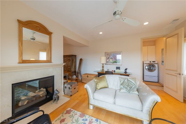 Primary bedroom sitting area with recessed lighting, washer / dryer, ceiling fan, a fireplace, and light wood-type flooring | Image 36