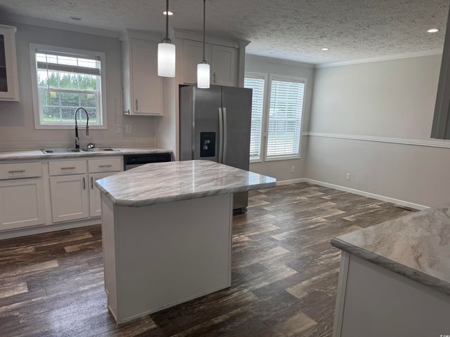 Kitchen featuring crown molding, stainless steel fridge, plenty of natural light, a kitchen island, and dark wood-type flooring | Image 16
