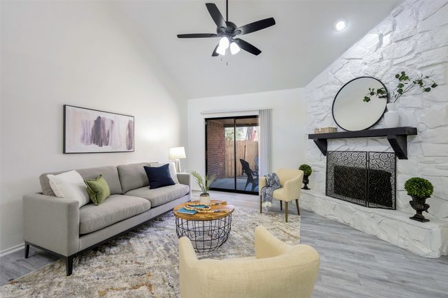 Living area with high vaulted ceiling, a large fireplace, a ceiling fan, and wood finished floors | Image 9