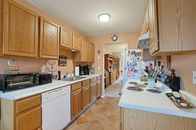 Kitchen featuring a sink, light countertops, white appliances, light brown cabinetry, and under cabinet range hood | Image 5