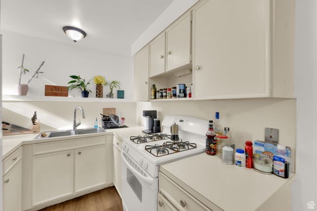 Kitchen with open shelves, white range with gas stovetop, light countertops, and light wood finished floors | Image 7