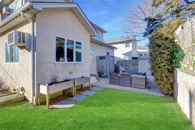 Rear view of house featuring an AC wall unit, a patio, an outdoor hangout area, and a lawn | Image 6