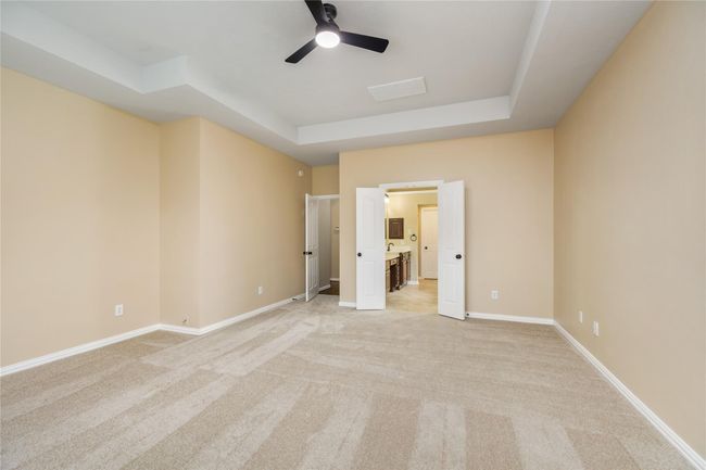 Filled with an abundance of natural light, this spacious primary bedroom has a double-door entry that leads into the en-suite bathroom, enhancing the bedroom’s open and connected feel. | Image 20