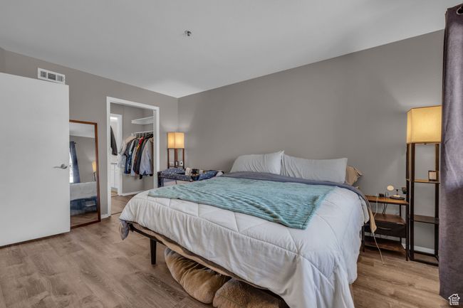 Bedroom featuring a walk in closet, light wood-style floors, a closet, and visible vents | Image 8