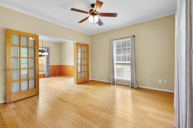 Second Living connection to formal dining featuring light wood-type flooring, crown molding, ceiling fan, french doors, and wooden walls | Image 11