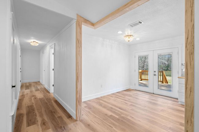 Hallway with visible vents, baseboards, ornamental molding, light wood-type flooring, and french doors | Image 17